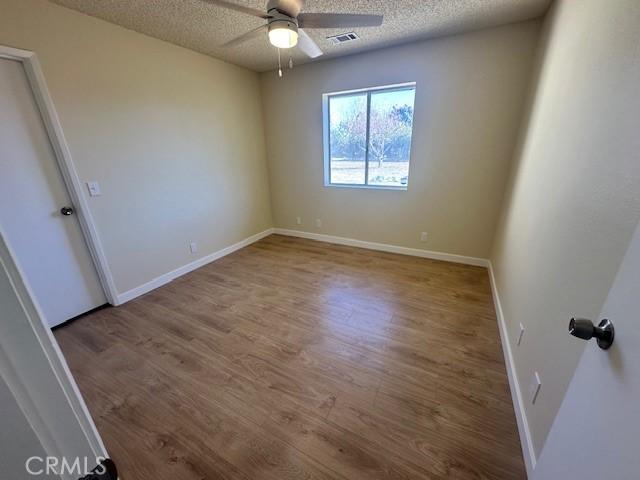 spare room featuring a textured ceiling, ceiling fan, and hardwood / wood-style flooring