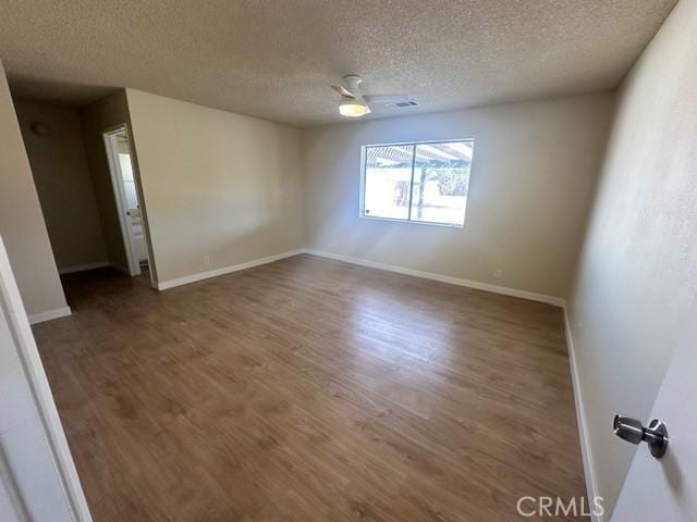 spare room with ceiling fan, dark wood-type flooring, and a textured ceiling