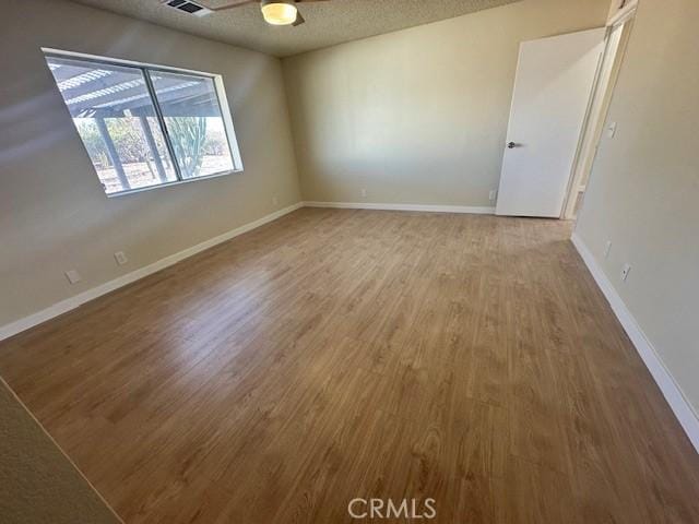 empty room with ceiling fan, hardwood / wood-style floors, and a textured ceiling