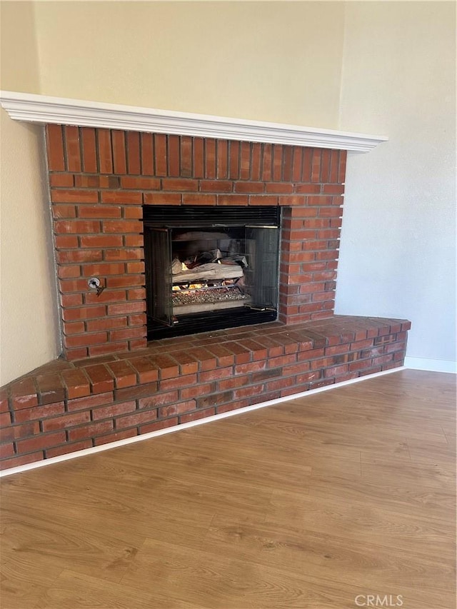 room details featuring a brick fireplace and wood-type flooring