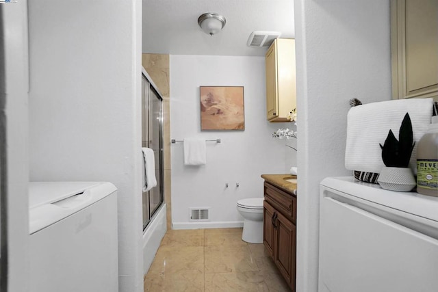 full bathroom featuring toilet, washer and dryer, enclosed tub / shower combo, tile patterned floors, and vanity