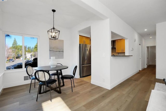 dining room featuring light wood-type flooring and an inviting chandelier