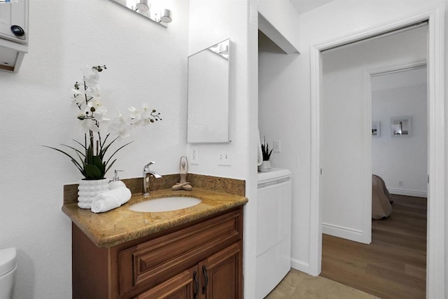 bathroom with toilet, hardwood / wood-style floors, and vanity