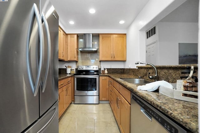 kitchen featuring dark stone countertops, stainless steel appliances, sink, wall chimney range hood, and light tile patterned flooring