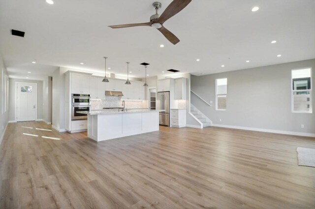 kitchen with white cabinetry, an island with sink, appliances with stainless steel finishes, tasteful backsplash, and pendant lighting