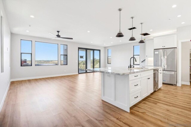 kitchen featuring a center island with sink, appliances with stainless steel finishes, hanging light fixtures, white cabinets, and sink