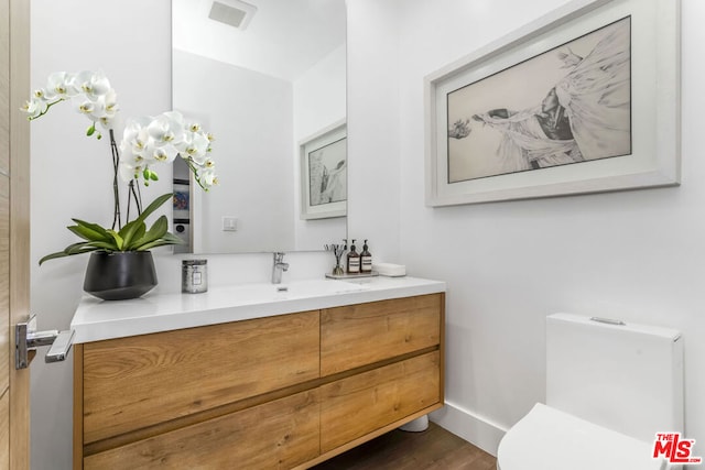 bathroom with wood-type flooring, toilet, and vanity