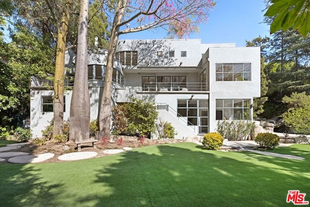 rear view of house with a balcony and a lawn