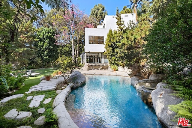 view of swimming pool with pool water feature and a yard