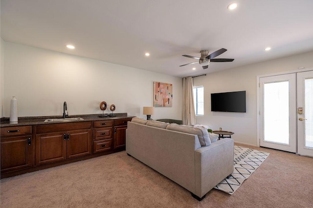 carpeted living room featuring ceiling fan, french doors, and sink