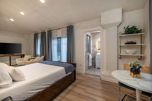 bedroom with a textured ceiling, hardwood / wood-style flooring, and ensuite bath