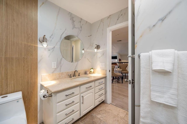 bathroom with toilet, vanity, and tile walls