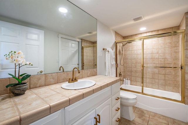 full bathroom featuring bath / shower combo with glass door, toilet, vanity, and tile patterned flooring