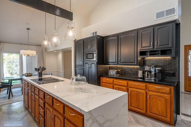 kitchen featuring pendant lighting, a kitchen island, light parquet flooring, black electric stovetop, and tasteful backsplash