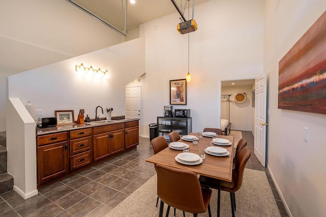 dining room featuring dark tile patterned flooring, sink, and a high ceiling