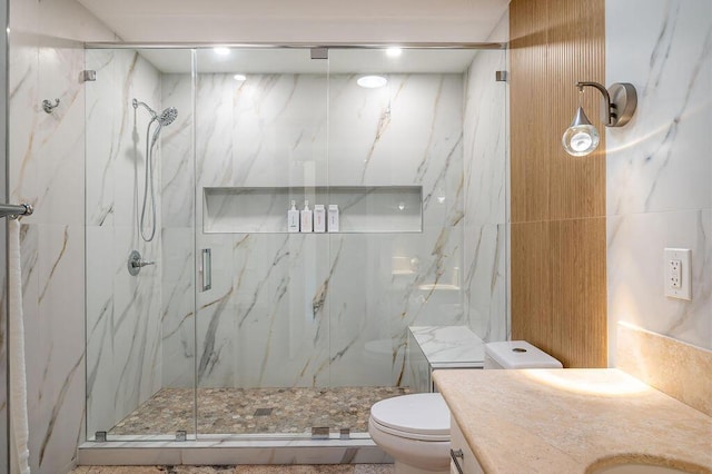 bathroom featuring a shower with shower door, vanity, and toilet