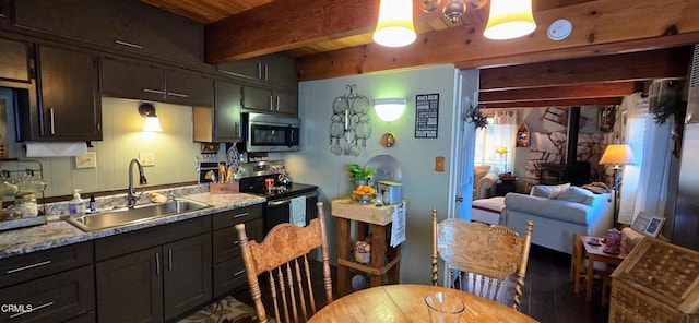 kitchen with stainless steel appliances, sink, a wood stove, and light stone countertops