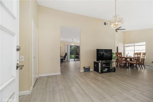 living room featuring ceiling fan with notable chandelier and light hardwood / wood-style flooring