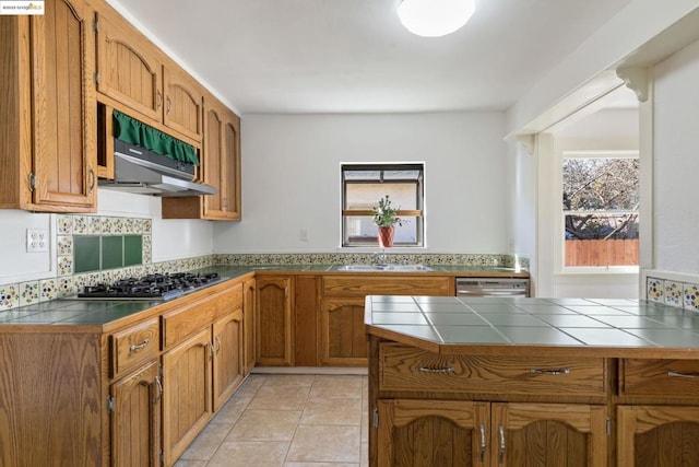 kitchen featuring appliances with stainless steel finishes, sink, kitchen peninsula, tile countertops, and light tile patterned floors