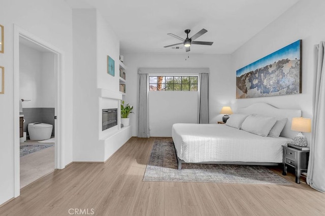 bedroom featuring ceiling fan, ensuite bathroom, and light hardwood / wood-style flooring