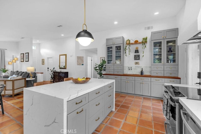 kitchen with a kitchen island, decorative light fixtures, electric stove, gray cabinets, and ventilation hood