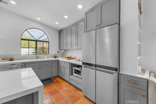 kitchen featuring gray cabinets, stainless steel appliances, light tile patterned flooring, light stone countertops, and sink