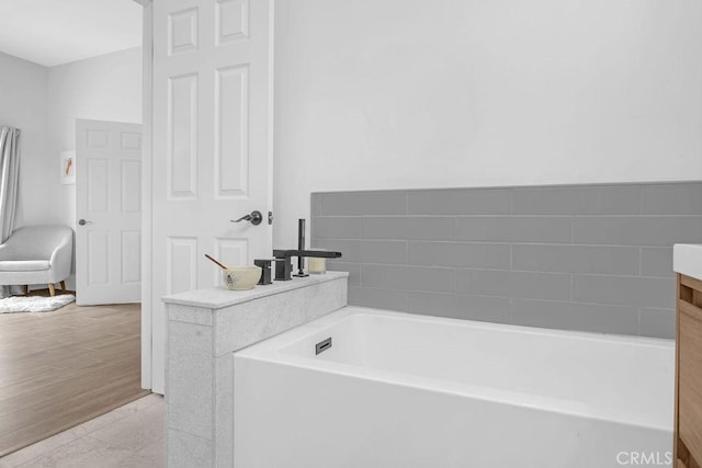 bathroom with tile patterned floors, a tub to relax in, and vanity