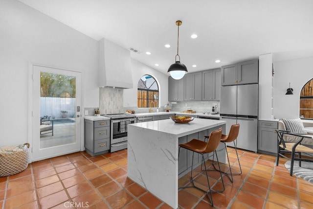 kitchen with stainless steel appliances, tasteful backsplash, a kitchen breakfast bar, hanging light fixtures, and gray cabinetry