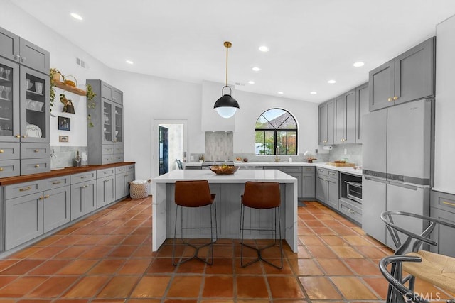 kitchen featuring a center island, white fridge, decorative backsplash, a kitchen breakfast bar, and gray cabinets