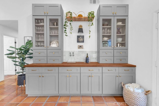 bar featuring light tile patterned floors, butcher block counters, and gray cabinets