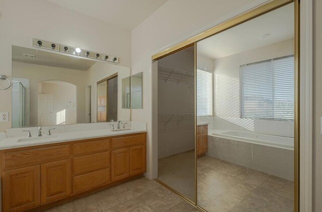 bathroom with vanity and a relaxing tiled tub