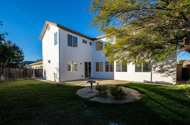 back of property featuring a patio area and a lawn