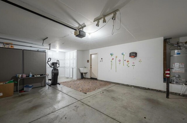 garage with a garage door opener, strapped water heater, and sink