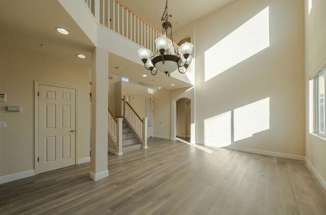 unfurnished living room with an inviting chandelier, hardwood / wood-style floors, and a high ceiling