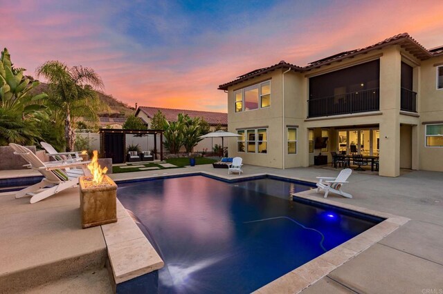 pool at dusk featuring a patio and a fire pit