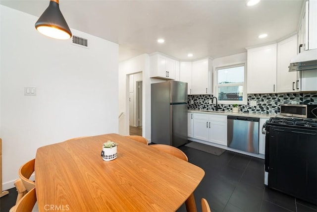 kitchen featuring pendant lighting, appliances with stainless steel finishes, white cabinetry, sink, and backsplash