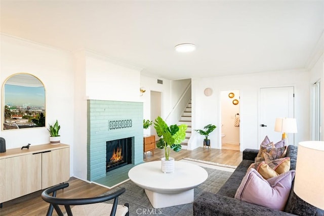 living room with ornamental molding, a fireplace, and wood-type flooring