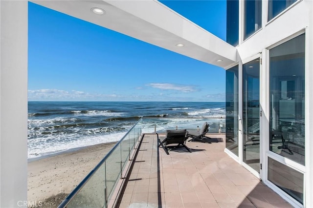 balcony featuring a water view and a view of the beach