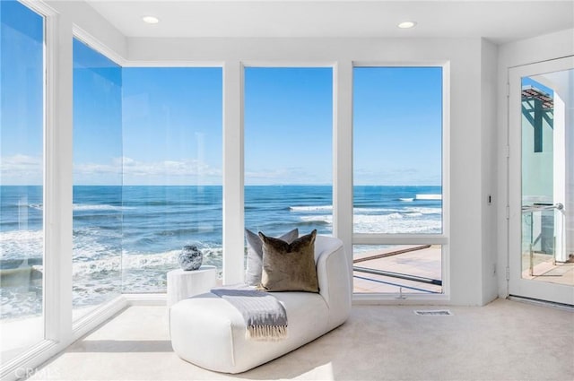 sunroom / solarium featuring a water view and a beach view