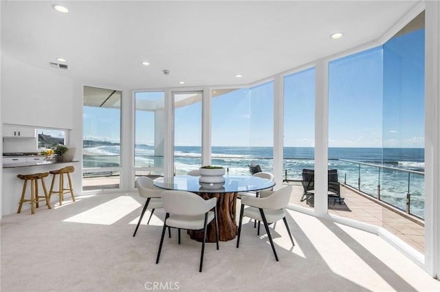 sunroom / solarium featuring a beach view and a water view