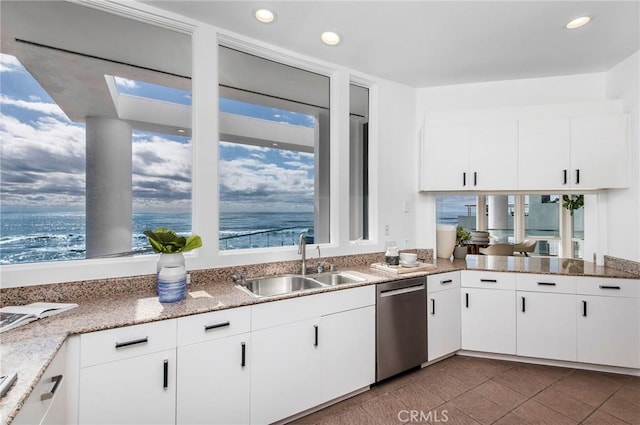 kitchen with light stone countertops, dishwasher, white cabinetry, sink, and a water view