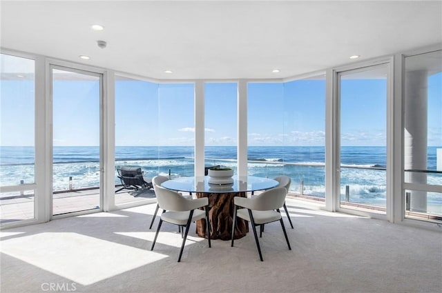 sunroom / solarium with a beach view, a water view, and plenty of natural light