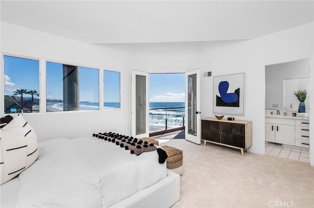 carpeted bedroom featuring a water view, vaulted ceiling, sink, and connected bathroom