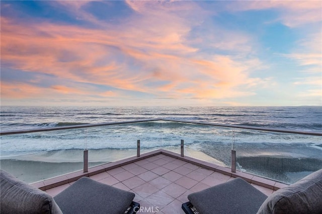 balcony at dusk with a water view and a beach view