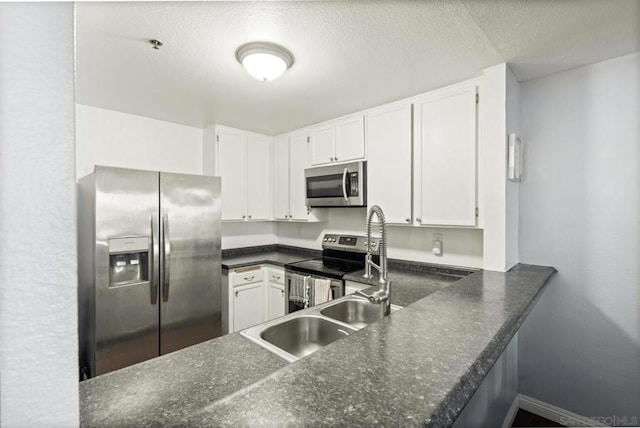 kitchen with stainless steel appliances, white cabinets, a textured ceiling, and kitchen peninsula