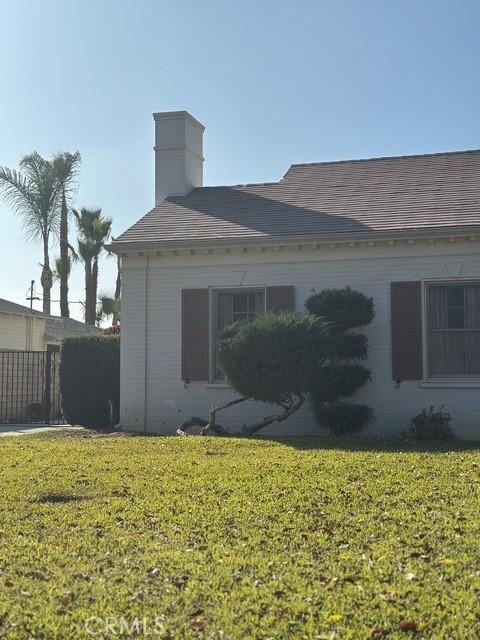 view of side of home featuring a shingled roof, a lawn, and fence