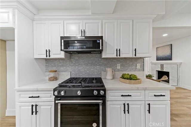 kitchen with white cabinetry, gas range, and tasteful backsplash