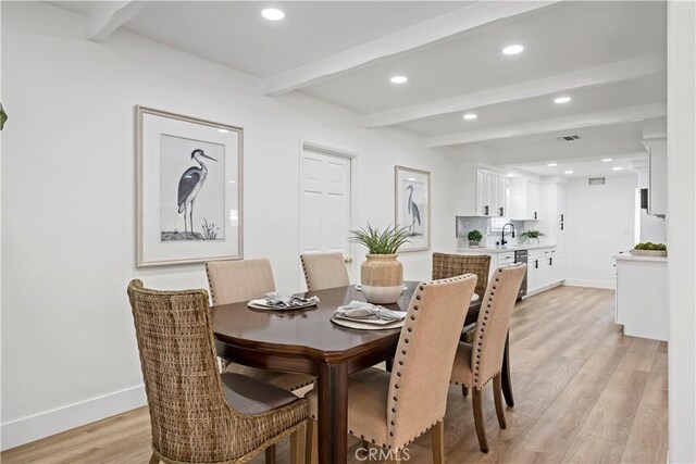 dining area with sink, beamed ceiling, and light hardwood / wood-style flooring