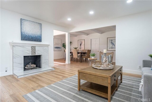 living room with a premium fireplace, hardwood / wood-style flooring, and beamed ceiling