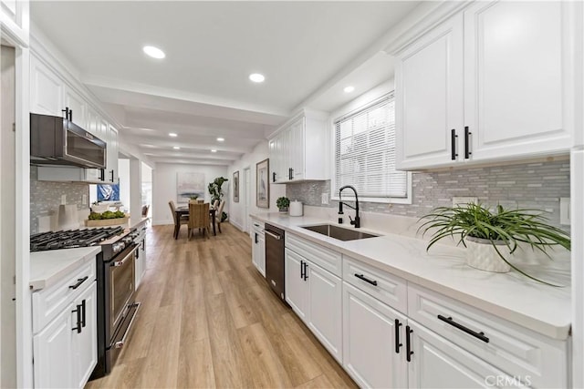 kitchen with white cabinets, light stone countertops, sink, and stainless steel appliances